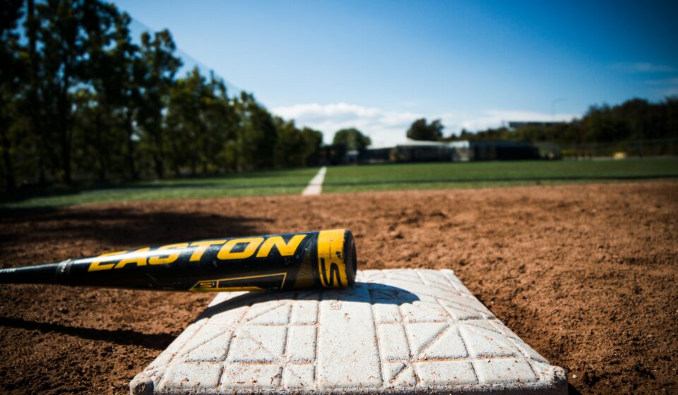 A bat lies on a base on a baseball field.
