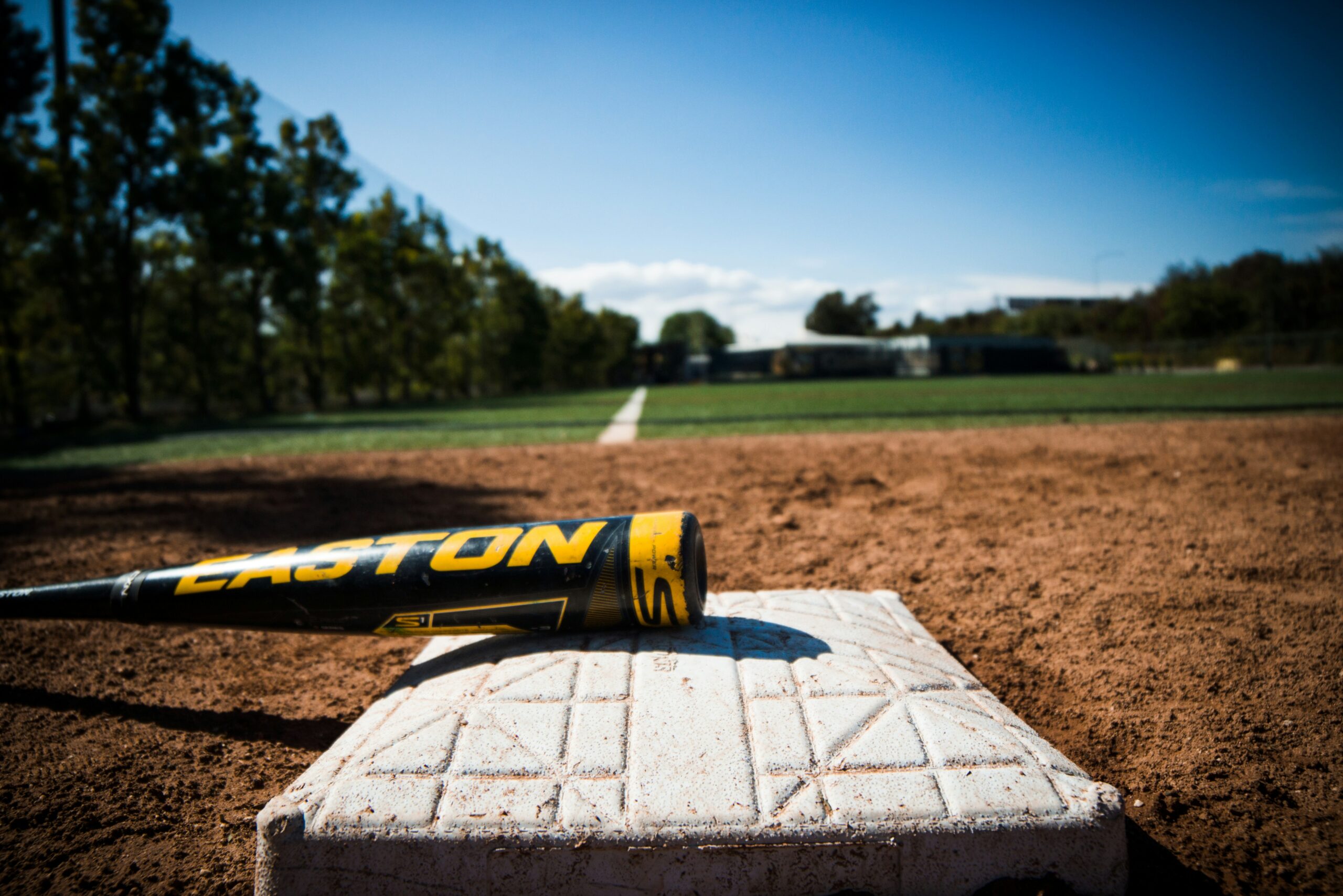 A bat lies on a base on a baseball field.