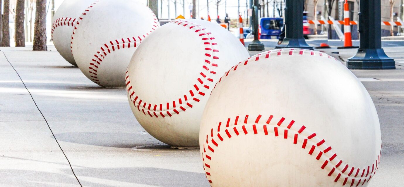 A row of oversized baseballs lines a sidewalk.
