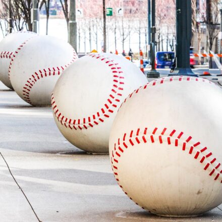 A row of oversized baseballs lines a sidewalk.