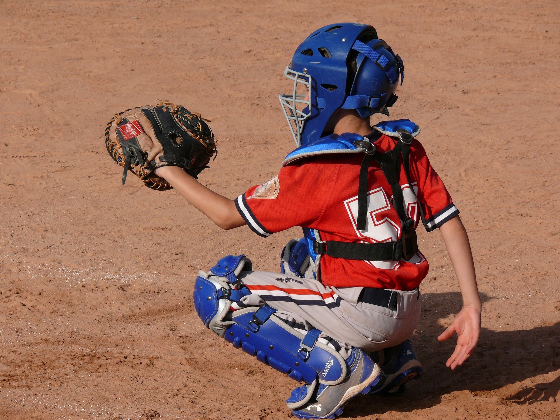 A crouching catcher raises his mitt.