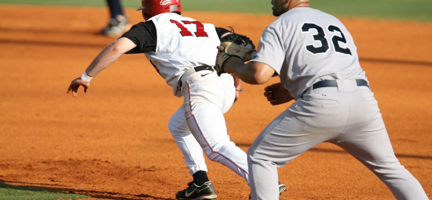 A runner races to the base while the infielder waits for the ball.