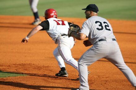 A runner races to the base while the infielder waits for the ball.