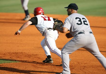 A runner races to the base while the infielder waits for the ball.