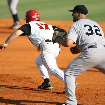 A runner races to the base while the infielder waits for the ball.