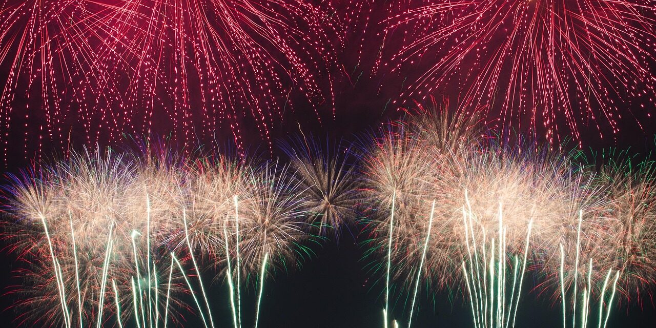 Red and white fireworks explode in the sky.