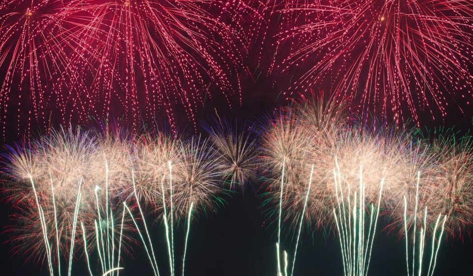 Red and white fireworks explode in the sky.