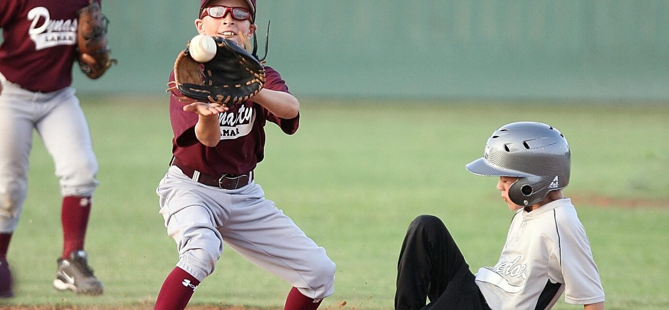 The infielder catches the ball too late, as the player sliding into base is safe.