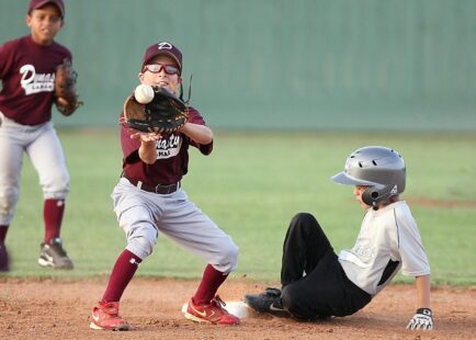 The infielder catches the ball too late, as the player sliding into base is safe.