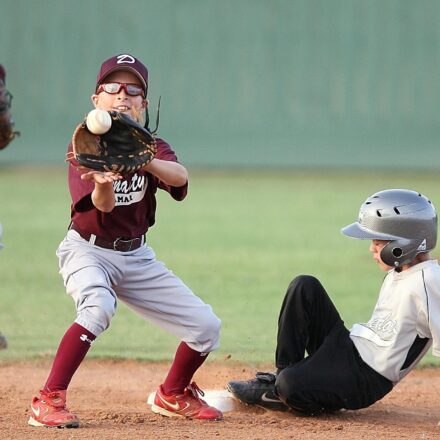 The infielder catches the ball too late, as the player sliding into base is safe.