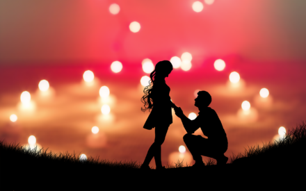 A man kneels in front of a woman with a vivid sky in the background.