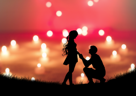 A man kneels in front of a woman with a vivid sky in the background.