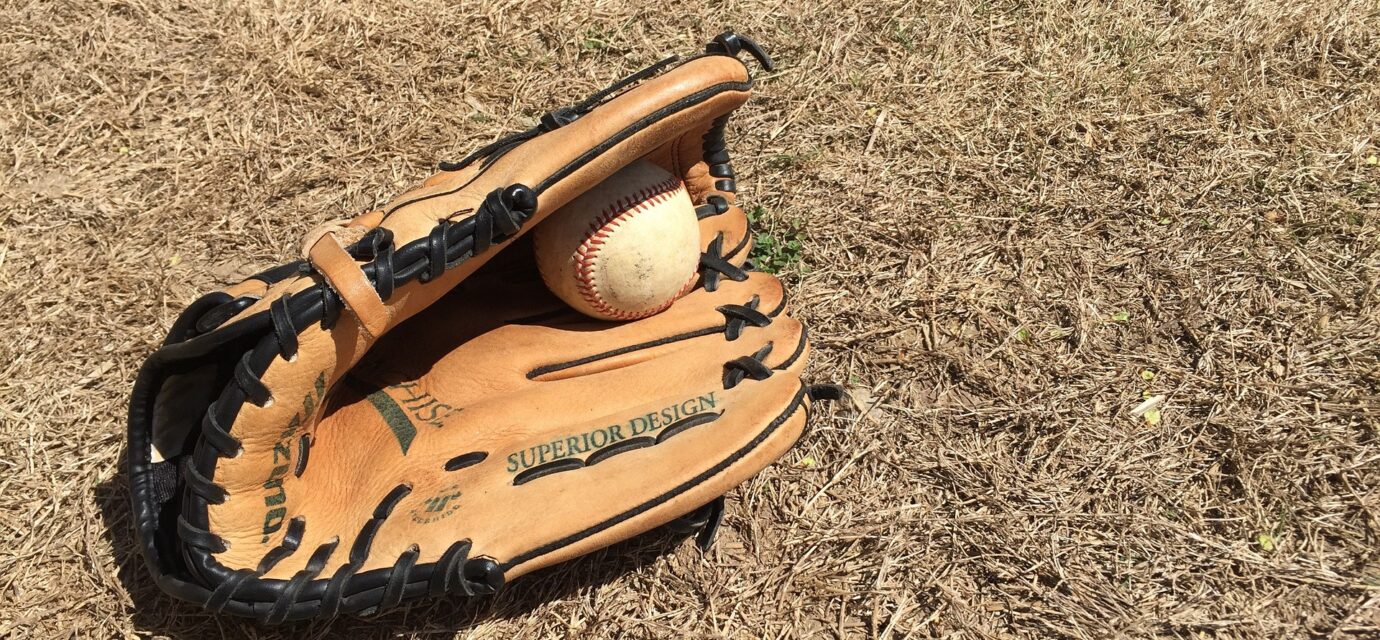 A glove with a baseball lie on the ground.