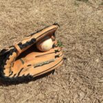 A glove with a baseball lie on the ground.