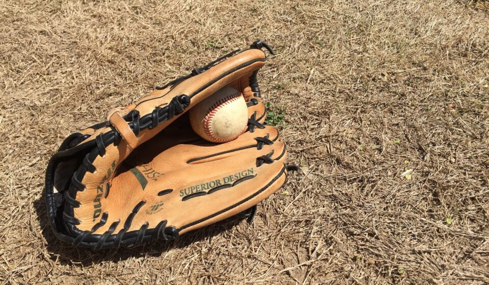 A glove with a baseball lie on the ground.