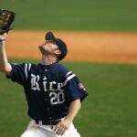 A baseball player raises his glove to catch the ball.