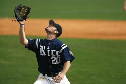 A baseball player raises his glove to catch the ball.