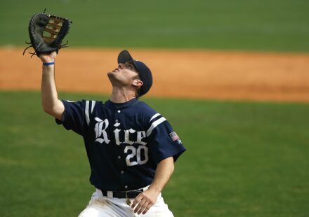 A baseball player raises his glove to catch the ball.
