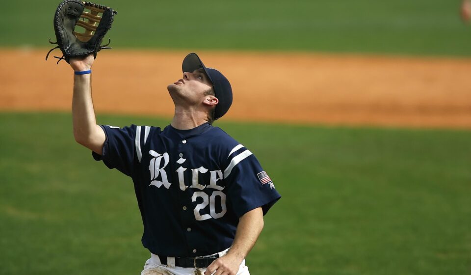 A baseball player raises his glove to catch the ball.