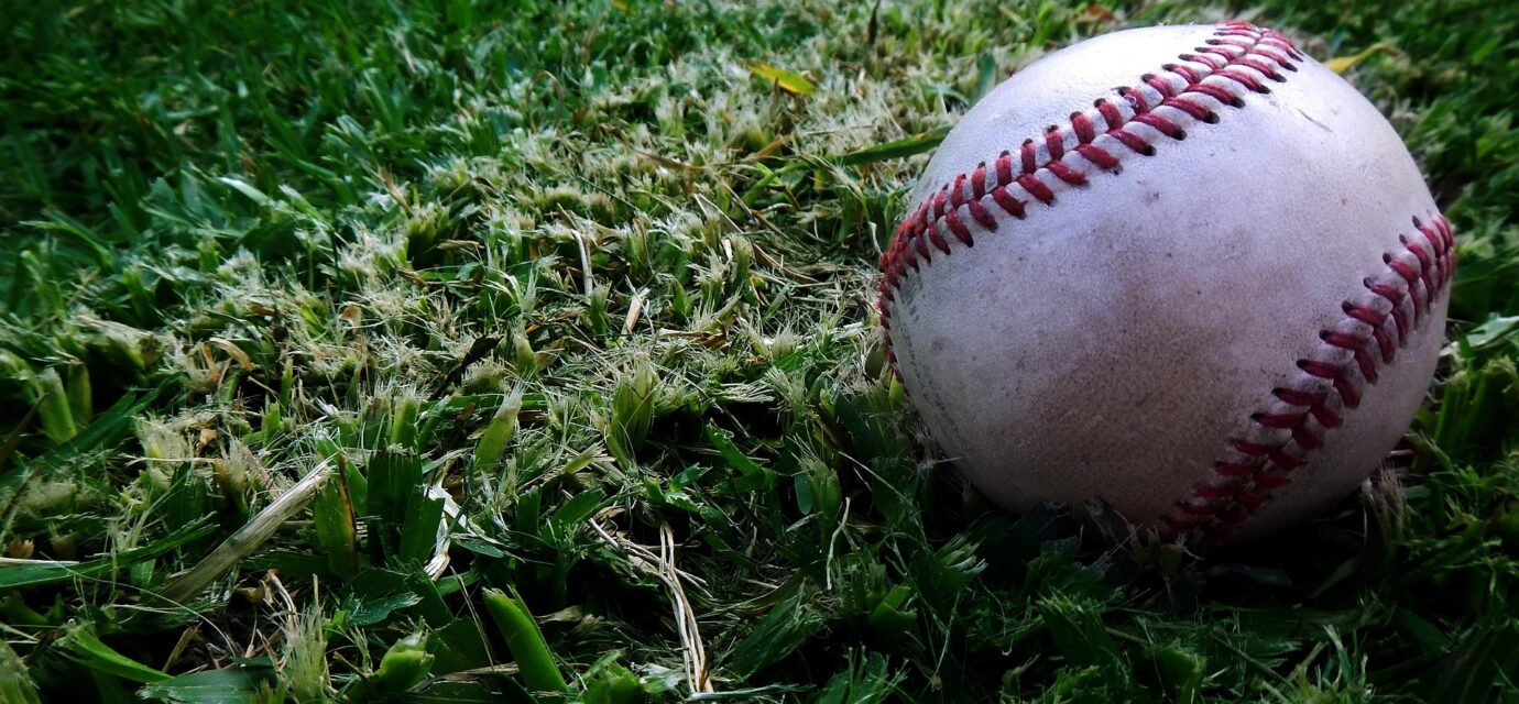 A baseball lies nestled in the grass.