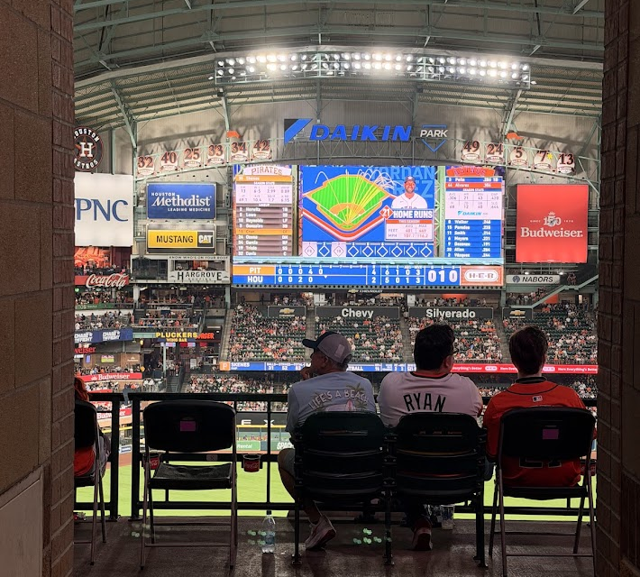 Astros fans sitting at Daikin Park, watching the big screen.