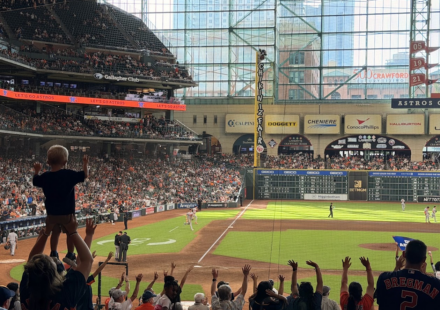 Fans cheer during an Astros game at Daikin Park as a child raises both arms in celebration.