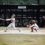 A baseball player swings at a pitch while the catcher receives the ball and the umpire watches from behind home plate.
