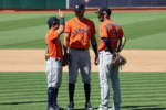 Carlos Correa stands with Jose Altuve and Marwin Gonzalez on the field during an Astros game.