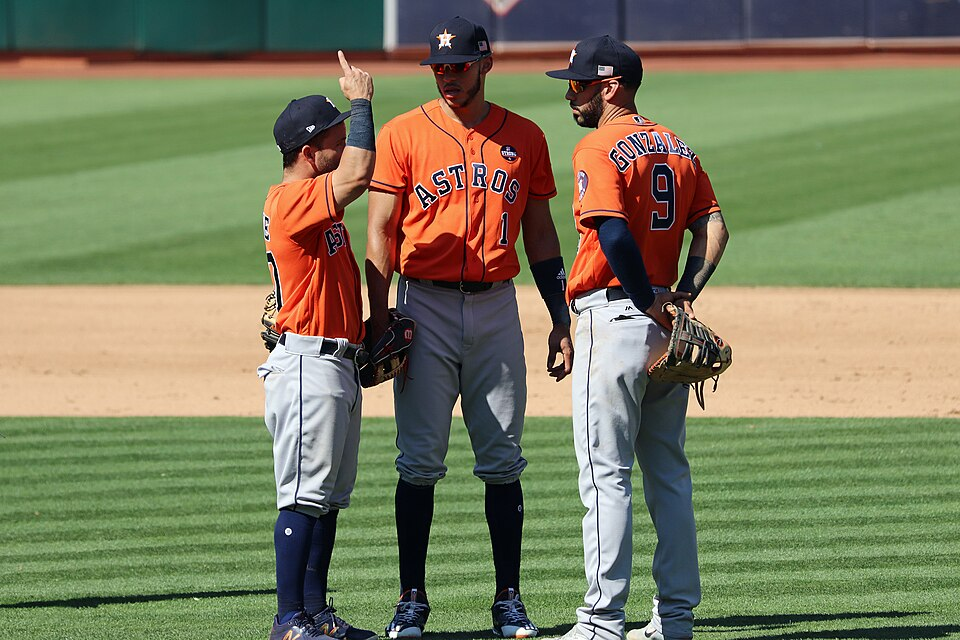 Carlos Correa stands with Jose Altuve and Marwin Gonzalez on the field during an Astros game.