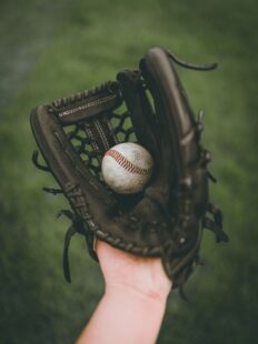 A hand in a baseball glove, holding a baseball.