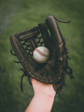 A hand in a baseball glove, holding a baseball.