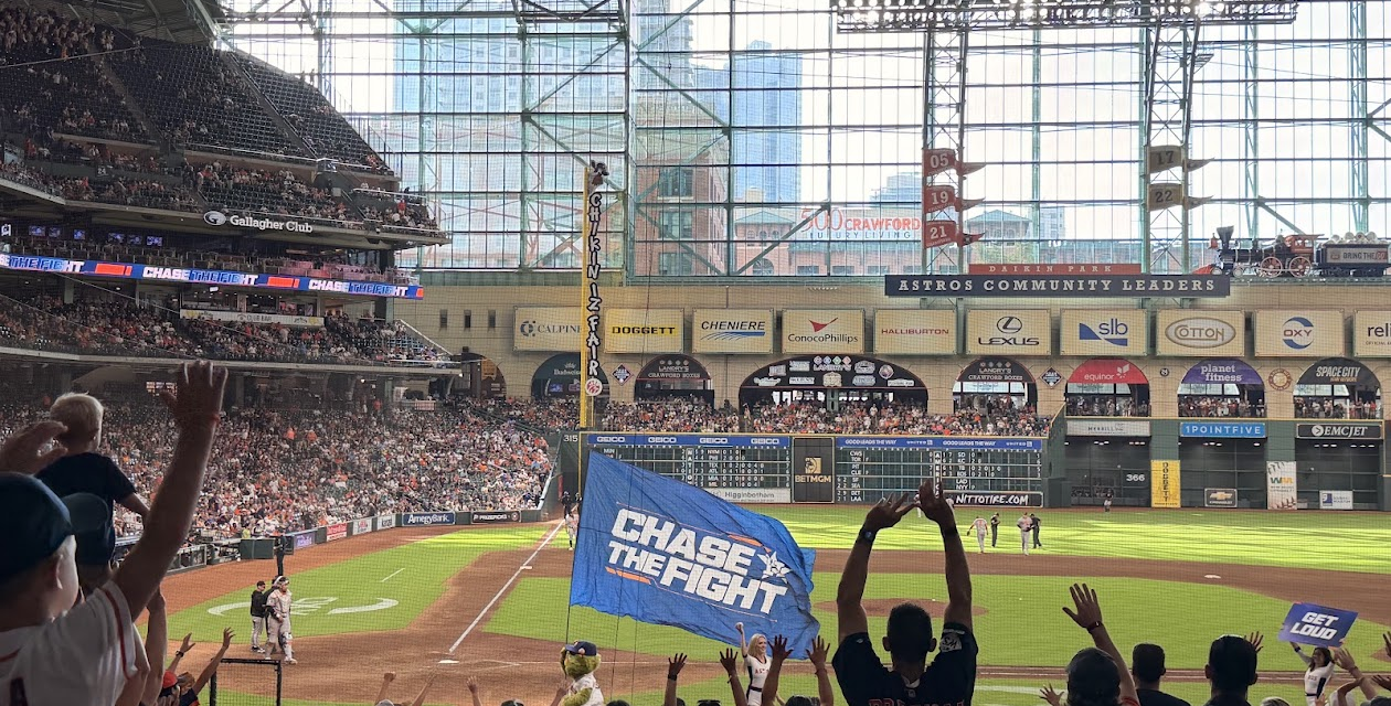 Astros mascot Orbit carries the "Chase the Fight" flag as fans cheer during a game at Daikin Park.