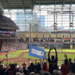 Astros mascot Orbit carries the "Chase the Fight" flag as fans cheer during a game at Daikin Park.
