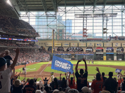 Astros mascot Orbit carries the "Chase the Fight" flag as fans cheer during a game at Daikin Park.