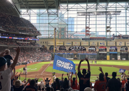 Astros mascot Orbit carries the "Chase the Fight" flag as fans cheer during a game at Daikin Park.