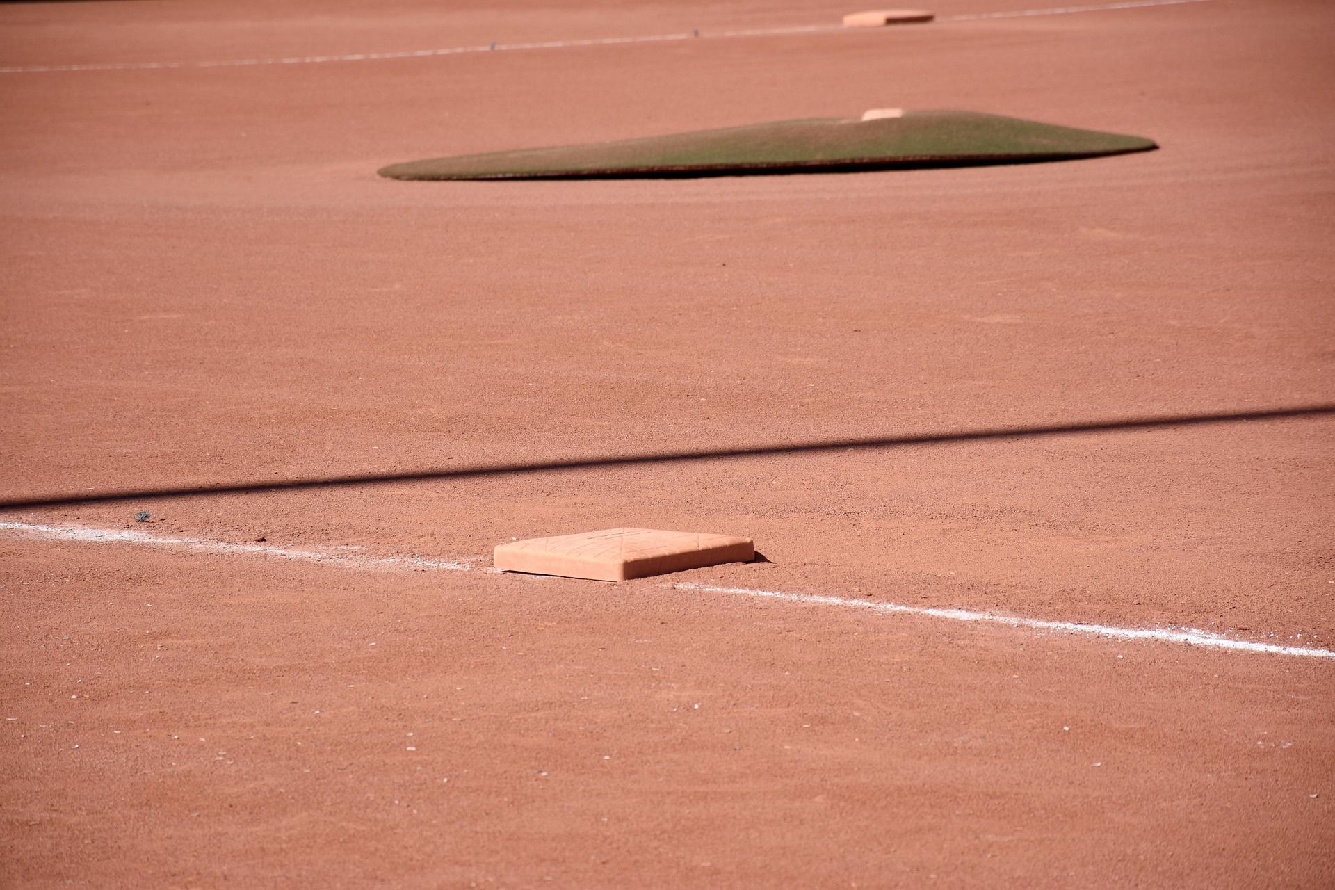 Baseball diamond with third base in the foreground and the pitcher’s mound in the distance.