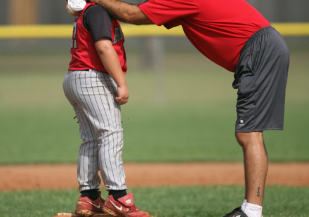 A baseball coach gives a player a pep talk.