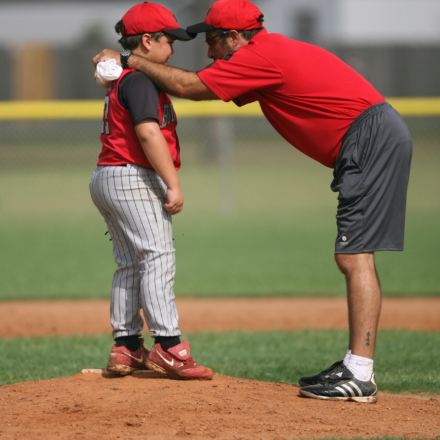 A baseball coach gives a player a pep talk.