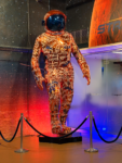 Astros astronaut statue covered in signatures and illuminated by orange and blue lights at Daikin Park.