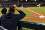 Baseball manager scratching his head in the dugout while looking toward an open first base.