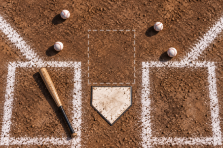 Four baseballs sit outside an illustrated strike zone above home plate, with a bat lying unused in the batter’s box.