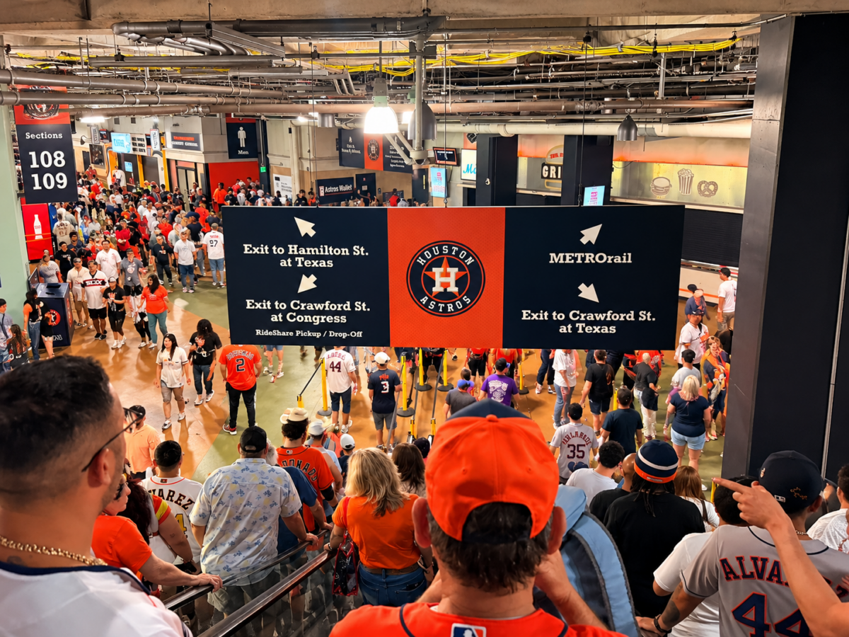 Astros fans exit Daikin Park following the team's final game of the 2026 season, beneath directional signs surrounding the Houston Astros logo.