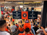 Astros fans exit Daikin Park following the team's final game of the 2026 season, beneath directional signs surrounding the Houston Astros logo.